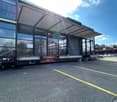 modern building with glass walls and roof, wide entrance, parking area