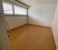 Empty room with hardwood floors, white walls, and white ceiling. A window with blinds and a radiator against the wall.