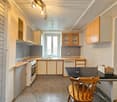 kitchen with built-in appliances, wooden cabinets, countertops, sink, dishwasher, refrigerator, and ceiling lamps