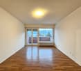 Empty room, white walls, wooden floor, glass sliding doors to a balcony, ceiling light