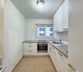 modern kitchen with built-in appliances, granite countertops, white cabinetry, windows, wooden floor