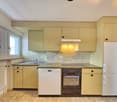 Modern kitchen with yellow cabinets, tiled floor, stainless steel sink, built-in dishwasher, electric stove, and refrigerator.