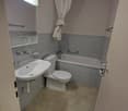 Bathroom with bathtub, toilet, sink, mirror, and blue tiles.