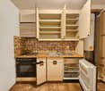 Open cupboards, sink, stove, fridge, cabinets, tile backsplash, wooden floors