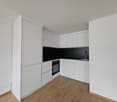 minimalist kitchen with oven, sink, wooden floor, white cabinets, black countertops