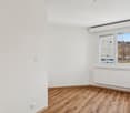 empty room with large window, wooden floor, white walls, radiator