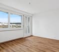 Empty room with large windows, hardwood floors, white walls, a heater and view of the city