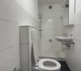 modern bathroom with white tiles, white toilet, white sink, shower, mirror, and black floor