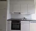 modern kitchen with white cabinets, black countertops, integrated oven and dishwasher, stainless steel sink and faucet
