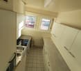 modern kitchen with white cabinets, tiled floor, double sink, gas stove, windows with blinds