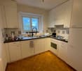 modern kitchen with white cabinets, wooden floor, white appliances, sink, oven, window