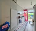 modern kitchen with white cabinets, tiled floor, dishwasher, oven, sink, countertop, pink curtains, glass door to balcony