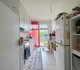modern kitchen with white cabinets, tiled floor, open door to garden, appliances, shelves with storage items