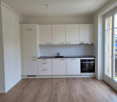 Spacious kitchen with white cabinets, black countertop, built-in oven, and hardwood flooring. Large window providing natural light.