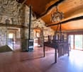Large room with exposed stone walls, wooden floor, chandelier, fireplace, staircase, balcony, sliding glass doors, balcony