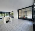 Empty room with white tiled floor, large glass windows, white walls, and a small white desk.