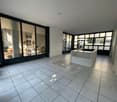 Empty room with white tiles, large windows, white reception desk, and a view of the outside