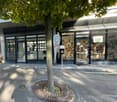 Modern building with glass walls, tree in the center, black metal grates, and a clock banner