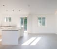 modern kitchen with island, white cabinets, granite countertop, built-in oven, sink, balcony with sliding glass door