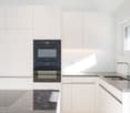 modern kitchen with white cabinets, granite countertops, double oven, sink, faucet, window