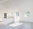 modern kitchen with island, white cabinets, granite countertop, built-in oven, sink, large windows, balcony