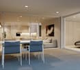 Dining area with a white table and chairs, glass walls, modern decor, and a view of the living room and kitchen.
