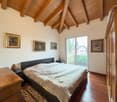 wooden floor, wooden ceiling, bed, nightstands, wooden cabinet, paintings, sliding glass door, balcony, rug