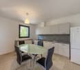 modern kitchen with white cabinets, gray countertops, glass table, and chairs