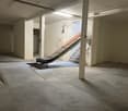 Empty garage with concrete floor, white walls, and a ramp for vehicle access.