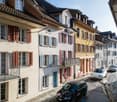 row of houses, balconies, parked cars, street lamps, red shutters, yellow star
