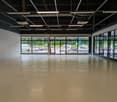 Empty room, concrete floor, large windows, parking area visible through windows