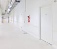 Long, white-walled hallway with a fire extinguisher mounted on the wall and a door labeled 'Lager'