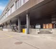 Large industrial building with loading docks, storage containers, and a parking area in front