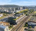 Aerial view of a city with modern buildings, trees, and a railway with a small building.
