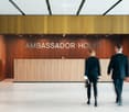 modern office entrance with wooden paneling, large sign reading 'AMBASSADOR HOUSE', and tiled floor