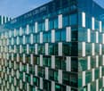 Large modern office building with glass facade, Funk Gruppe logo visible, multiple floors, parking spaces visible in front of the building