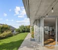 modern house, large windows, open sliding glass door, terrace, grass lawn, plants, concrete walkway