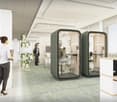 a modern office with several work pods, carpeted floor, a large window, and a desk area.