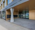 Modern building with glass doors, concrete column, mailboxes, and a paved entrance area.