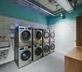 tiled floor, stack of washing machines, sink, wooden cabinet, tiled wall, ventilation ducting