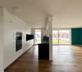 modern kitchen with white cabinets, black countertops, wooden floor, large windows, built-in oven and dishwasher