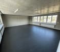 empty room with large windows, concrete floor, large ceiling lamp, white walls, white window frames, and white radiators