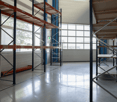 Empty room with a large window, metal racks, and industrial shelving.