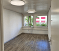 an empty room with white walls, wooden floor, two windows with balcony, two ceiling lights