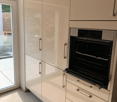 modern kitchen with white cabinets, glass door, open oven, and white tiled floor