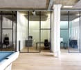 Spacious open plan office with glass walls, hardwood flooring, large desk, and a pool table in the corner.