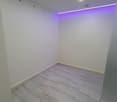 Empty room with white walls and marble flooring, recessed lighting and purple light strip on the ceiling.