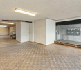 spacious corridor with concrete flooring, white walls, ceiling lights, mail slots, and a fire extinguisher