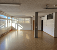 Open room with parquet floor, windows, column, ceiling lamps
