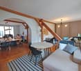 large open room with wooden floor, modern furniture, desks, couches, windows, plants